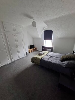 A bedroom with a bed, a TV, a wardrobe, and a window. - Alice Place 4BR Long-term Stay Parking, Wifi (Sunderland)