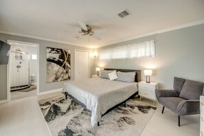 Ein Schlafzimmer mit einem Bett, Nachttischlampen, einem Deckenventilator und einem Duschbereich.