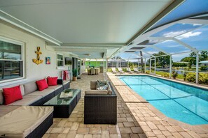 A covered outdoor area with a pool, seating, and a view of the surrounding landscape. - Villa Laetitia-on water, pool, boat dock (Cape Coral)