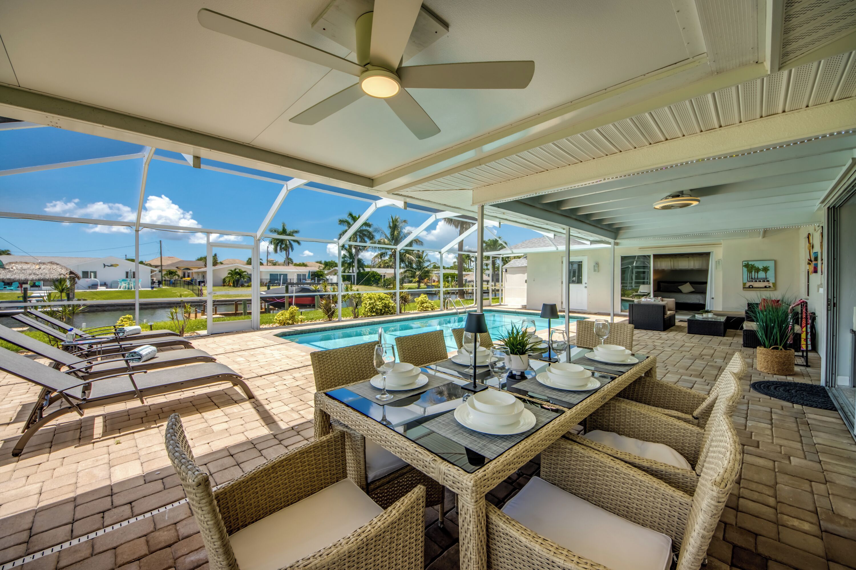 An outdoor dining area with a pool, lounge chairs, and a ceiling fan.