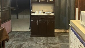 Una cocina con un mueble de madera oscura, un microondas y un piso de baldosas.