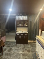 Una cocina con un mueble de madera oscura, un microondas y un piso de baldosas.