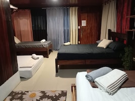 Una habitación con dos camas, cabecero de madera, una mesita y una cortina.