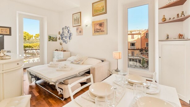 Una habitación de hotel con cama, mesita de noche, lámpara y vistas de la ciudad a través de una ventana.