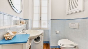 Un baño con lavabo, lavadora, inodoro y ventana.