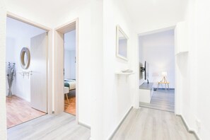 Een gang met een bed, een spiegel, een televisie en een lamp.