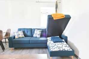 Ein modernes Wohnzimmer mit einem blauen Sofa, gemusterten Kissen und einem Beistelltisch.