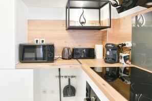 Eine kleine Küche mit Mikrowelle, Toaster, Wasserkocher und Kaffeemaschine auf einer Holz Arbeitsplatte.