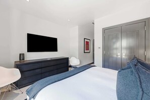 Une chambre à coucher moderne, comprenant un lit, une commode, une chaise, un téléviseur et une porte.
