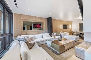 Ein modernes Wohnzimmer mit einer Eckcouch, einem Couchtisch und einem an der Wand montierten Fernseher.