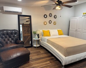 A bedroom with a bed, a leather armchair, a small table with a lamp, and a ceiling fan. - My Lily Apartment 8 Min Stadium 10 Airport 12 Zoo (Tampa)