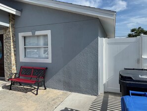 A residential exterior with a grey textured wall, a white window, a red bench, and a white gate. - My Lily Apartment 8 Min Stadium 10 Airport 12 Zoo (Tampa)
