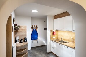 A compact kitchen with white cabinets, a wooden countertop, and a built-in sink. - Apartment 'Binterhof Alpin Deluxe' with Mountain View, Balcony and Wi-Fi (Kastelruth)