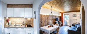 Eine moderne Küche mit weißen Schränken und einem Essbereich mit einem Holztisch und Stühlen.