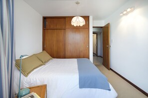 A bedroom with a bed, a wardrobe, a bedside table, and a hanging light fixture. - Central, spacious and comfortable (San Carlos de Bariloche)