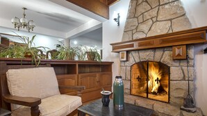 Un interior acogedor con chimenea de piedra, muebles de madera y un ventilador de techo.