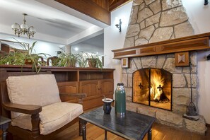 Ein gemütliches Interieur mit Kamin aus Stein, Holzmöbeln und Deckenventilator.