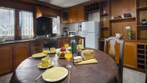 Un comedor con una mesa preparada para el desayuno, incluyendo pan, fruta y bebidas.