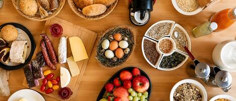 A breakfast table with various food items, including bread, eggs, cheese, fruits, and beverages.