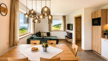 A modern kitchen with wooden cabinets, a built-in oven, and a dining area with a table set for two.