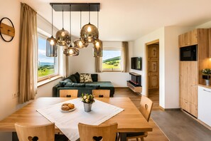 A modern kitchen with wooden cabinets, a built-in oven, and a dining area with a table set for two. - Apartment 'Binterhof Genziana' with Mountain View, Private Terrace and Wi-Fi (Kastelruth)