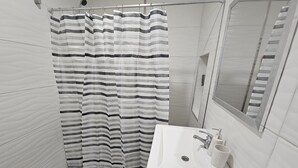 A bathroom with a shower curtain, a sink, a mirror, and a towel. - Canto de Aguila Bariloche (San Carlos de Bariloche)