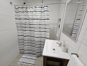 A bathroom with a shower curtain, a sink, a mirror, and a towel. - Canto de Aguila Bariloche (San Carlos de Bariloche)