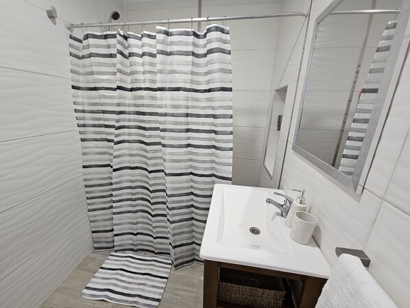 Ein Badezimmer mit Duschvorhang, Waschbecken, Spiegel und Handtuch.