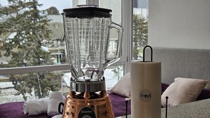 A kitchen with a blender on the counter, a roll of paper towels, and a window with a view of trees and buildings. - Canto de Aguila Bariloche (San Carlos de Bariloche)