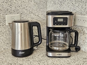 A coffee maker with a glass carafe and a stainless steel kettle on a granite countertop. - Canto de Aguila Bariloche (San Carlos de Bariloche)