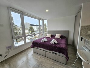 A bedroom with a large window, a bed with a headboard, and a built-in bench. - Canto de Aguila Bariloche (San Carlos de Bariloche)