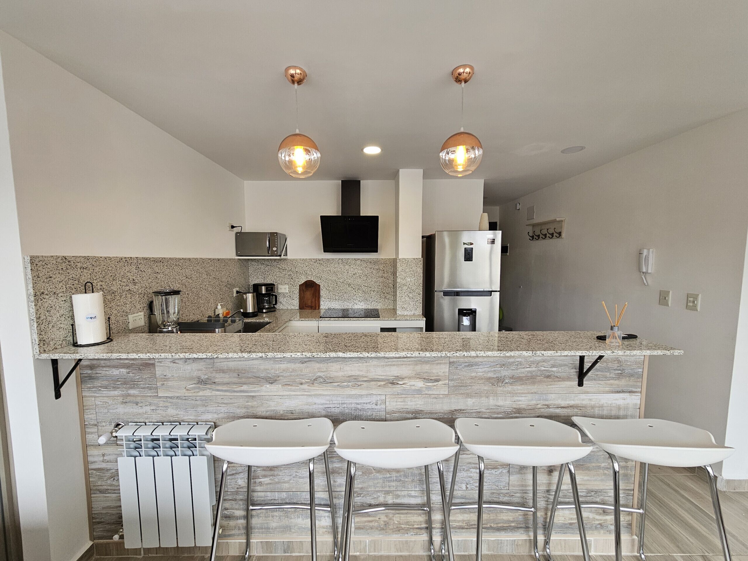 A modern kitchen with a central island, stainless steel appliances, and bar stools.