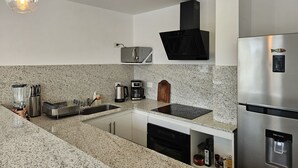 A modern kitchen with granite countertops, stainless steel appliances, and pendant lighting. - Canto de Aguila Bariloche (San Carlos de Bariloche)