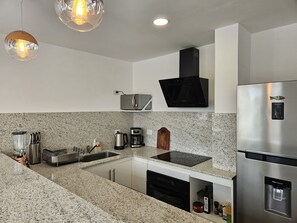 A modern kitchen with granite countertops, stainless steel appliances, and pendant lighting. - Canto de Aguila Bariloche (San Carlos de Bariloche)