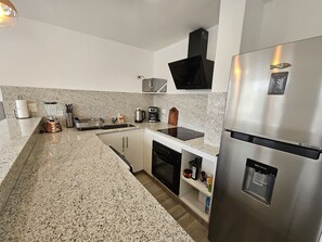 Eine moderne Küche mit Granit Arbeitsplatten, Edelstahlgeräten und einem eingebauten Backofen.