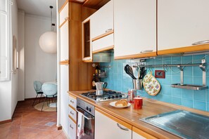 Une cuisine avec des armoires en bois, une cuisinière et un dosseret de carrelage bleu.