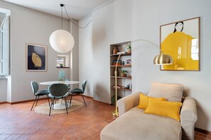 A modern living room with a sofa, a dining table with chairs, a bookshelf, and a pendant light. - 'Classy City-center Oasis' Apartment with Wi-Fi and Air Conditioning (Lucca)