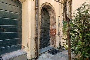 A building entrance with a metal door, a stone archway, and a small step leading to the door. - 'Classy City-center Oasis' Apartment with Wi-Fi and Air Conditioning (Lucca)