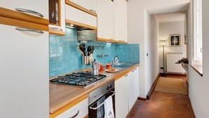 A kitchen with white cabinets, a blue tiled backsplash, a gas stove, and a coffee maker. - 'Classy City-center Oasis' Apartment with Wi-Fi and Air Conditioning (Lucca)