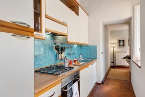 Eine Küche mit weißen Schränken, einer blauen Fliesenrückwand, einem Gasherd und einer Kaffeemaschine.
