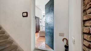 A hallway with a number plate, a wooden door, a staircase, and a brick wall. - 'Classy City-center Oasis' Apartment with Wi-Fi and Air Conditioning (Lucca)