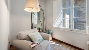 A room with a sofa, a lamp, a mirror, a window, and a potted plant. - 'Classy City-center Oasis' Apartment with Wi-Fi and Air Conditioning (Lucca)
