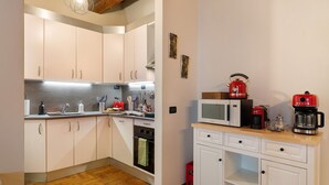 A compact kitchen with white cabinets, a microwave, a red coffee maker, and a wooden countertop. - Apartment "Casa Conrad - Lucca" with Wi-Fi and Air Conditioning (Lucca)