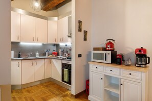 A compact kitchen with white cabinets, a microwave, a red coffee maker, and a wooden countertop. - Apartment "Casa Conrad - Lucca" with Wi-Fi and Air Conditioning (Lucca)