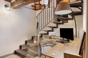 En modern inredning med en spiraltrappa, ett skrivbord med en dator och en lampa.