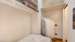 A small, compact room with a single bed, a towel on the bed, and a closet with a hanging rack. - Apartment "Casa Conrad - Lucca" with Wi-Fi and Air Conditioning (Lucca)