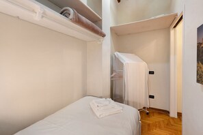 A small, compact room with a single bed, a towel on the bed, and a closet with a hanging rack. - Apartment "Casa Conrad - Lucca" with Wi-Fi and Air Conditioning (Lucca)