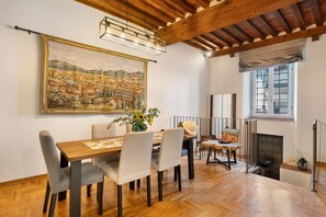 Un comedor con una mesa de madera, sillas y un cuadro de paisaje urbano en la pared.