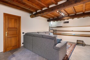 A room with a wooden ceiling, a grey sofa, a small table, and a patterned rug. - Apartment "Casa Conrad - Lucca" with Wi-Fi and Air Conditioning (Lucca)