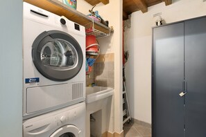A laundry room with a front-loading washing machine, a dryer, a sink, and a dark-colored cabinet. - Apartment "Casa Conrad - Lucca" with Wi-Fi and Air Conditioning (Lucca)